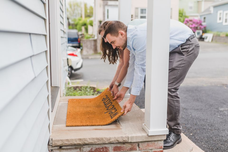 Couple setting out a welcome mat at their home